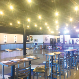 Interior of Game Changer Sports Bar & Grill in Londonderry. Chrome bar seating, an open floor with rows of cornhole boards.