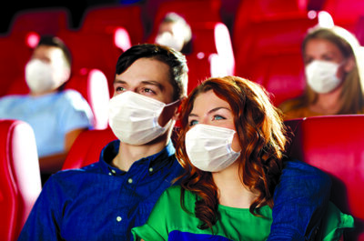 cinema, entertainment and pandemic concept - couple wearing face protective medical masks for protection from virus disease watching movie in theater