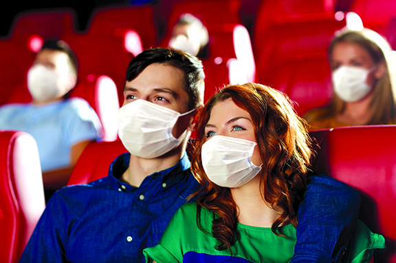cinema, entertainment and pandemic concept - couple wearing face protective medical masks for protection from virus disease watching movie in theater
