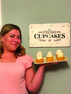 women holding a tray of cupcakes