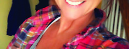 young woman in plaid shirt smiling at camera