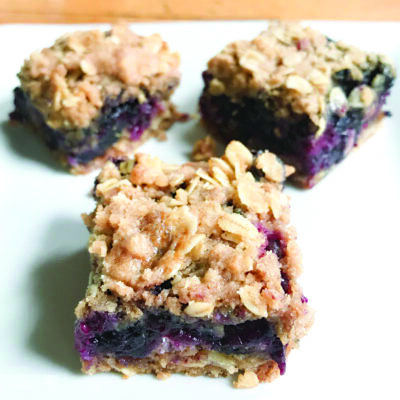3 baked blueberry and oat squares sitting on white surface