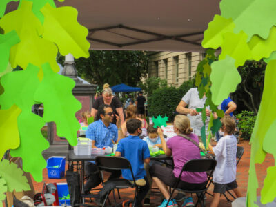 adults and children gathered around table doing paper crafts