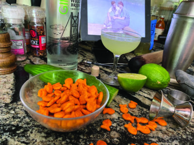 wine glass surrounded by limes and a bowl of goldfish snacks