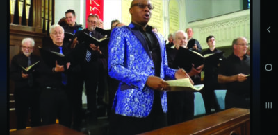 men's choir holding songbooks and singing in a church