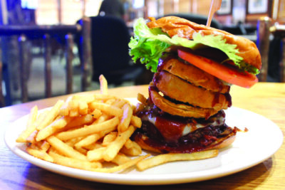 plate on table with french fries and tall barbeque burger topped with lettuce and tomato