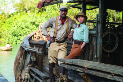 still from Jungle Cruise movie, man and woman posing on wooden boat, old fashioned clothing
