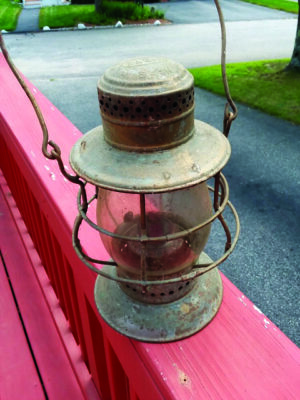 old metal and glass lantern sitting on porch railing