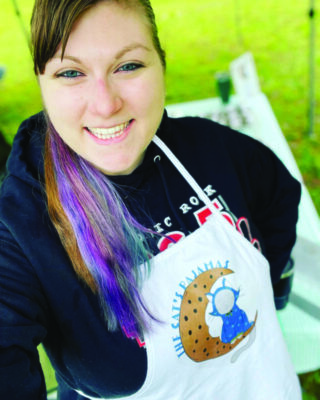 selfie of young woman with rainbow colored ponytail, outside, wearing cooking apron