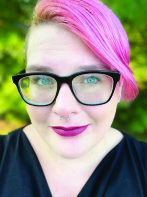portrait of woman with glasses and pink hair, outside