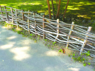 stick fence built on border between pavement and grassy yard