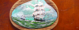 miniature painting of ship, painted on sea shell, sitting on wood
