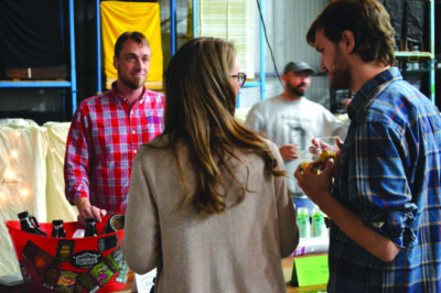 man and woman speaking with man serving beer at festival table