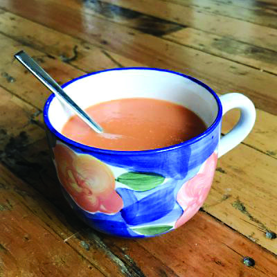 creamy soup in flowered mug, on wooden table