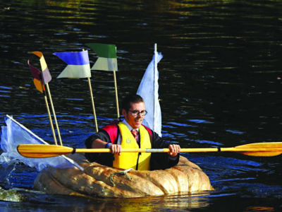 man in costume paddling in giant pumpkin boat