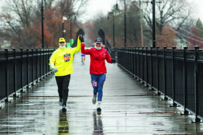 2 runners in raincoats, raising hands and smiling, rainy day