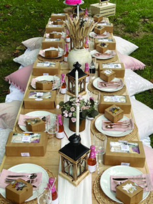 long wooden table on grass, set with plates and decorative centerpieces