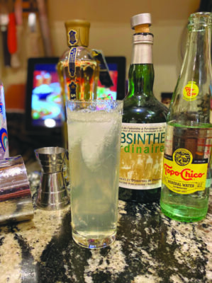 tall drink glass on marble counter, surrounded by cocktail ingredients