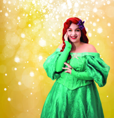 young woman dresses as a Disney princess, smiling, standing in front of sparkly background