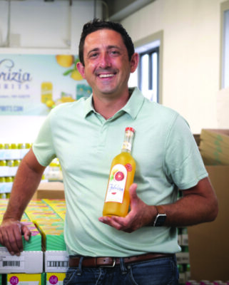 dark haired man in polo shirt and jeans, holding a bottle of limoncello from Fabrizia Spirits