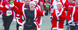group of runners dressed in Santa costumes, in street race