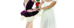 two dancers dressed for performance in The Nutcracker ballet, posing on white background