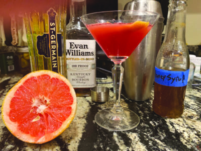 grapefruit, liquor bottles and martini glass on stone counter