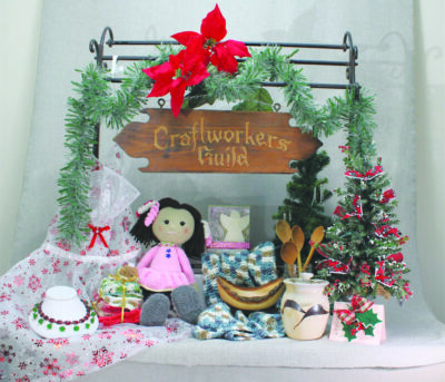 Miniature display of crafts including doll, necklace, holiday trees, topped with sign that reads Craftworker's Guild