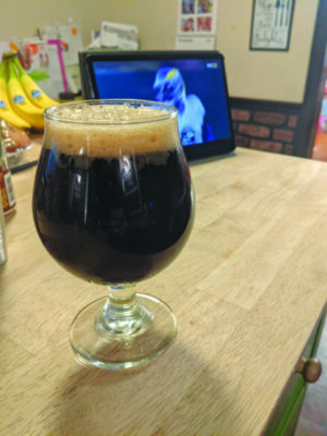 glass of coffee and beer on table, football playing on screen in background