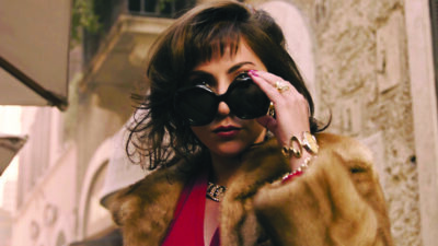 Still from House of Gucci, woman in fur coat taking off her sunglasses