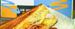 ham and grilled cheese sandwich in front of Prime Time Grilled Cheese restaurant sign