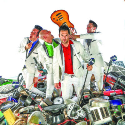 Recycled Percussion band members pose on a pile of scrap metal