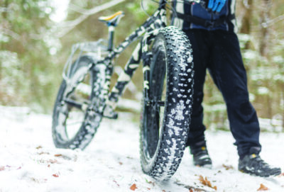 man standing with bike with fat wheels on snowy trail
