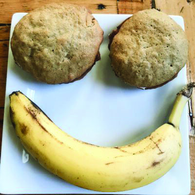 2 banana whoopie pies on plate, positioned over banana to create illusion of smiley face