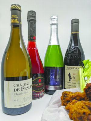 assortment of bottled wines beside plate of chicken wings