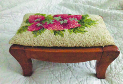 short wooden footstool with embroidered top cushion, flower decoration