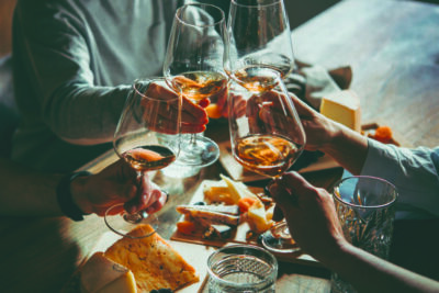 group of people around a table, clinking wine glasses in toast