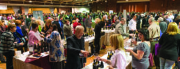 event room filled with wine sampling tables, large crowd