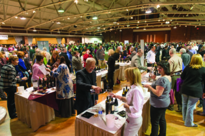 event room filled with wine sampling tables, large crowd