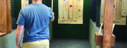 man at indoor ax throwing venue, holding ax, preparing to throw at target
