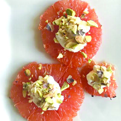 slices of grapefruit topped with yogurt and pistachio mix