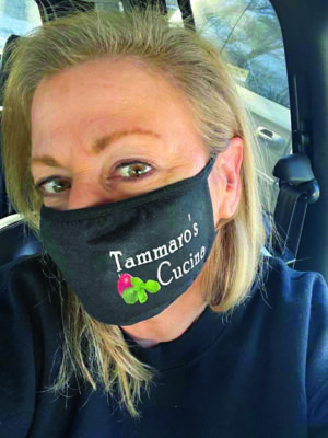 woman taking selfie in car, wearing mask with logo for Tammaro's Cucuna