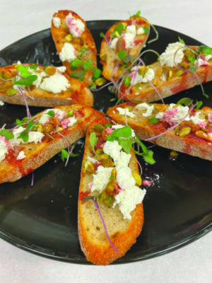 Pomegranate pistachio crostini with goat cheese arranged on a round plate