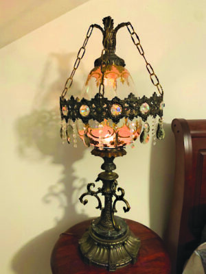 bronze decorative lamp sitting on small table beside bed