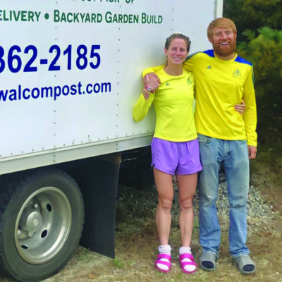 man and woman standing in front of composting truck