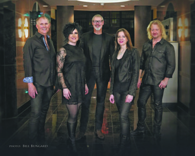 5 band members dressed in black posing in hallway