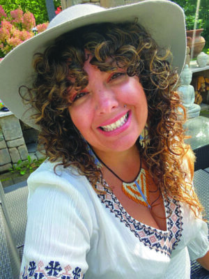 smiling woman wearing broad brimmed hat and embroidered shirt, outside