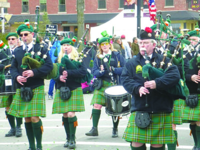 bagpipe players wearing kilts, walking down street in parade