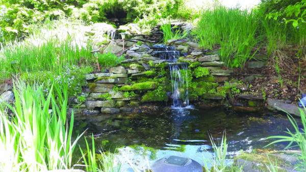 garden waterfall made of stacked stones, running into small pond