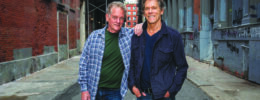 Micheal and Kevin Bacon of the band Bacon Brothers, posing in empty street, smiling